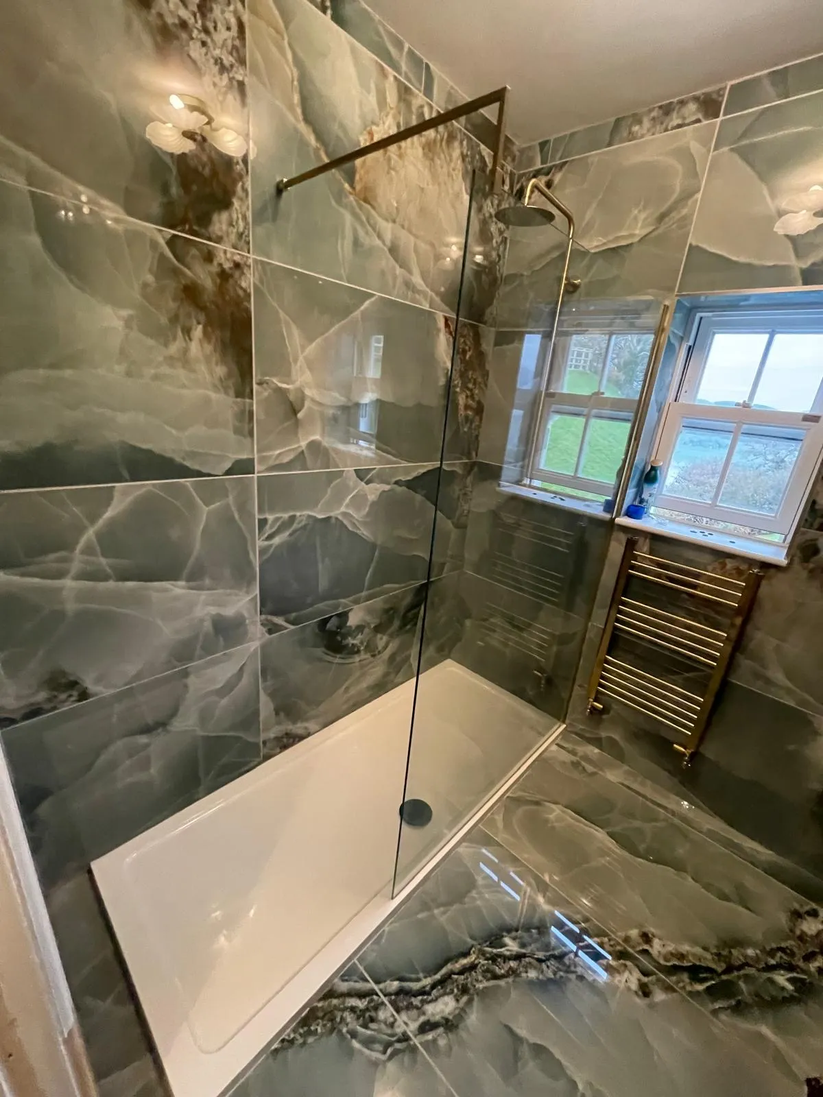 Green onyx walk-in shower with brass fittings installed in Gwynedd