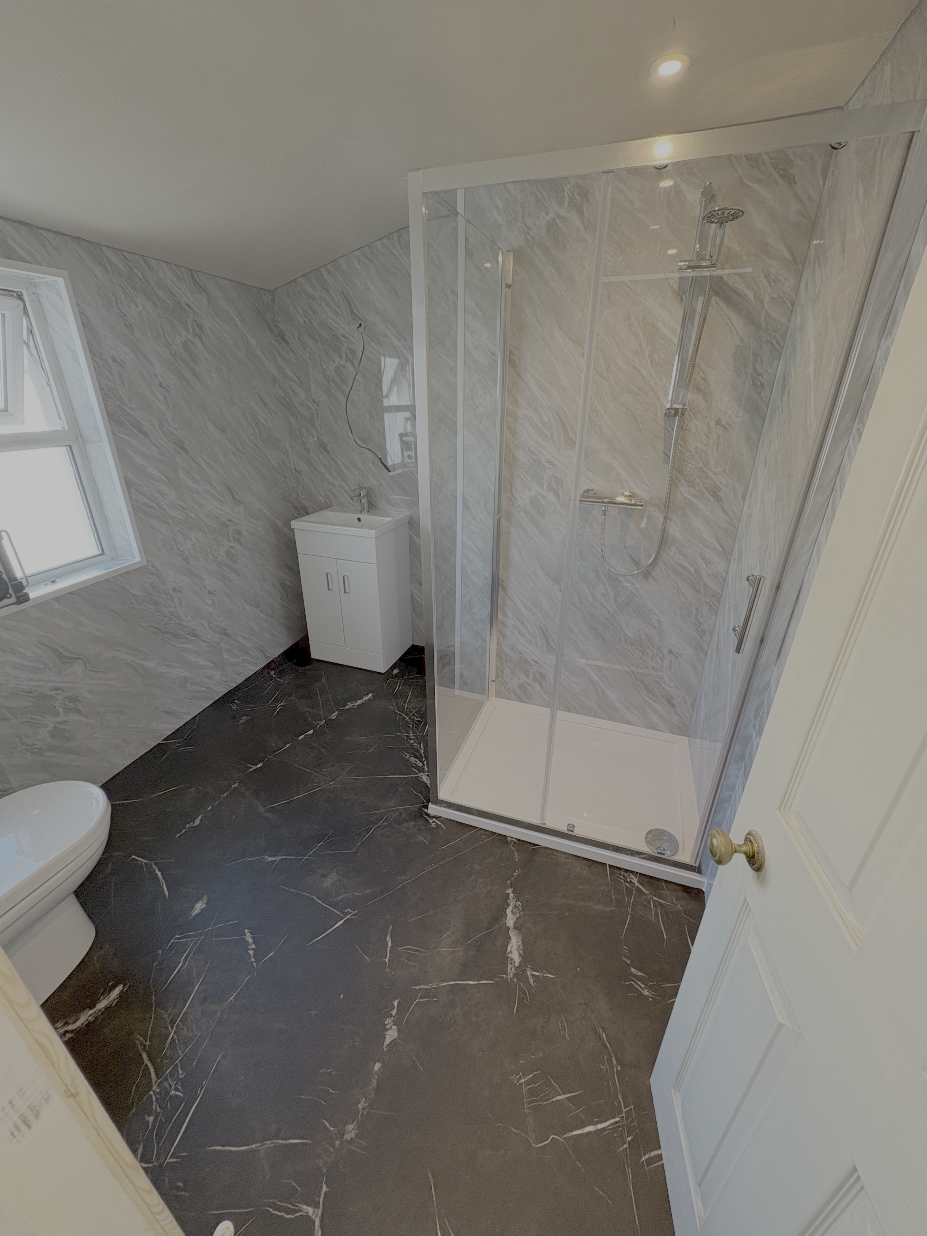 Shower room after CR Plumbing refit — grey marble panels and new enclosure