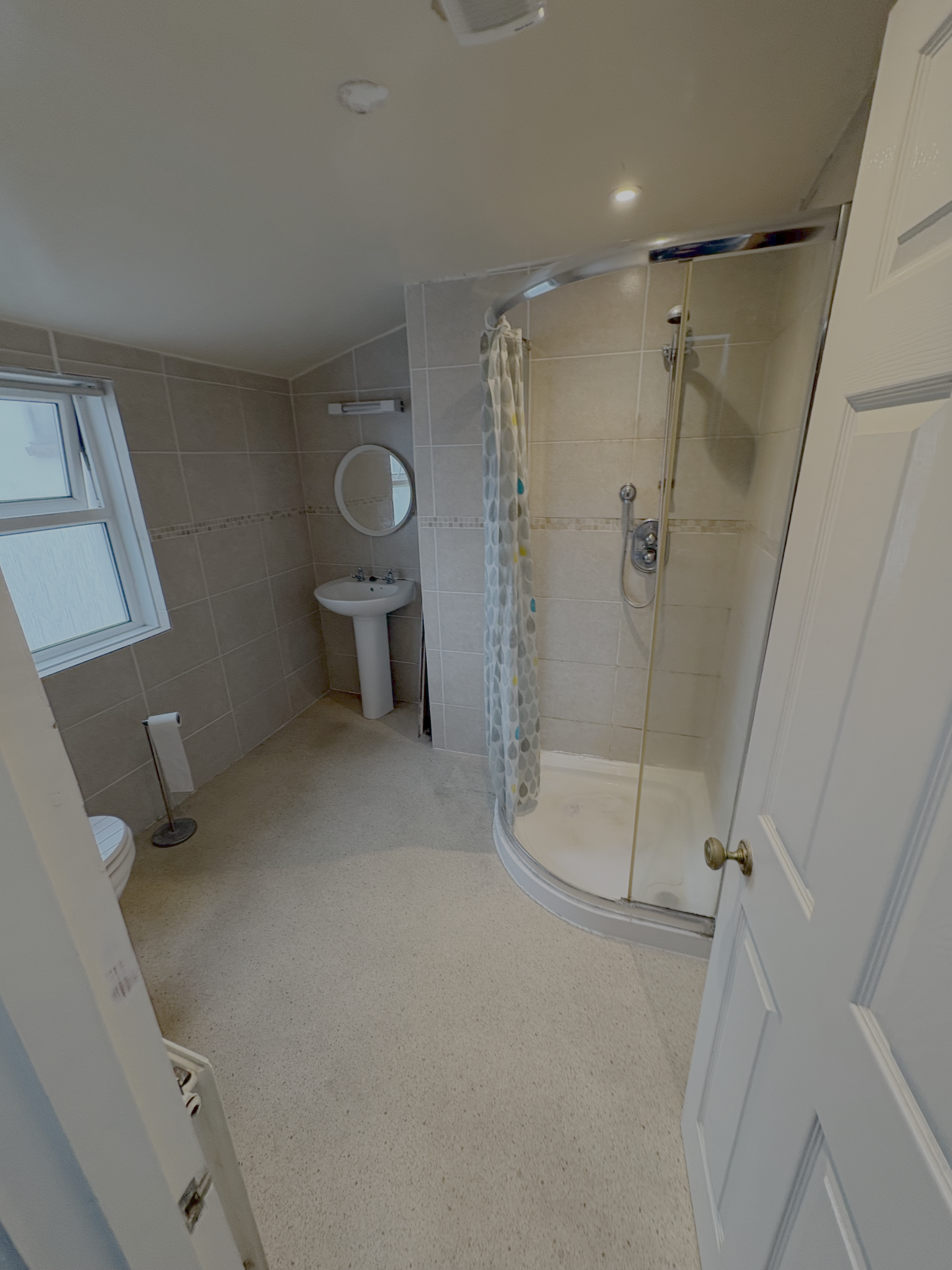 The same shower room before the refit — beige tiles and quadrant enclosure