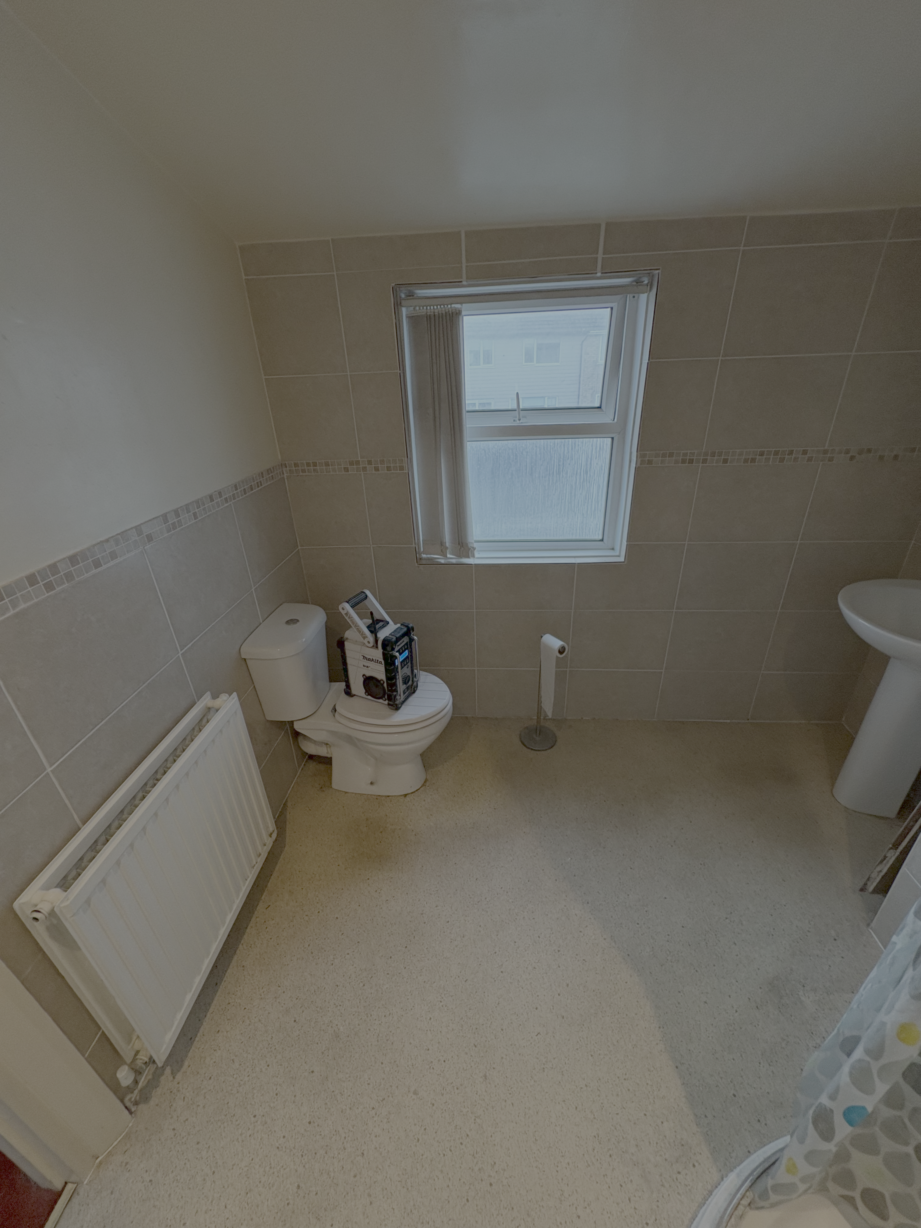 The same bathroom before the refit — dated beige wall tiles and vinyl floor